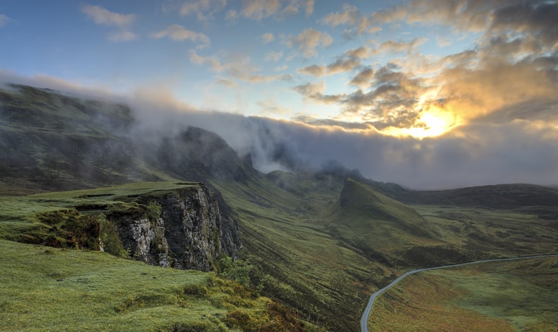 Green mountain valley with mist rolling over grassy ridges at sunrise
